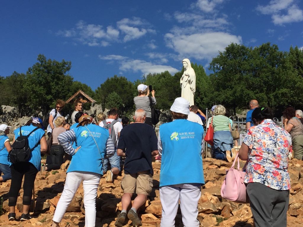 Peregrinos orando ante la estatua de la Virgen en Podbrdo